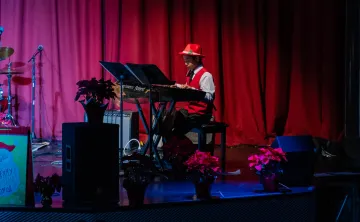 Child playing piano on stage during a holiday performance