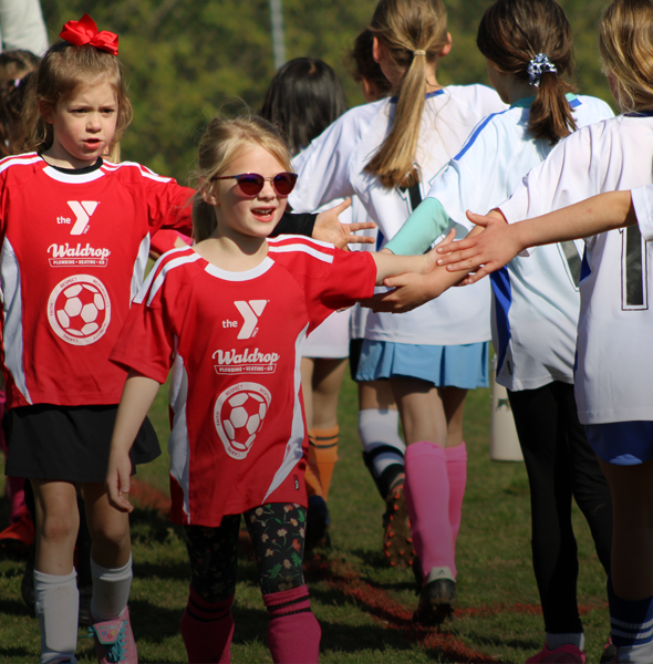 Girl Y soccer players high fiving after a game