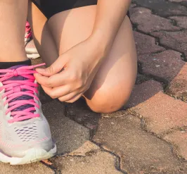 two hands tying laces on a running shoes on a brick ground