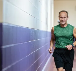 an older man running around an indoor track