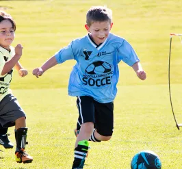 five young boys in soccer jerseys playing a competitive game of soccer