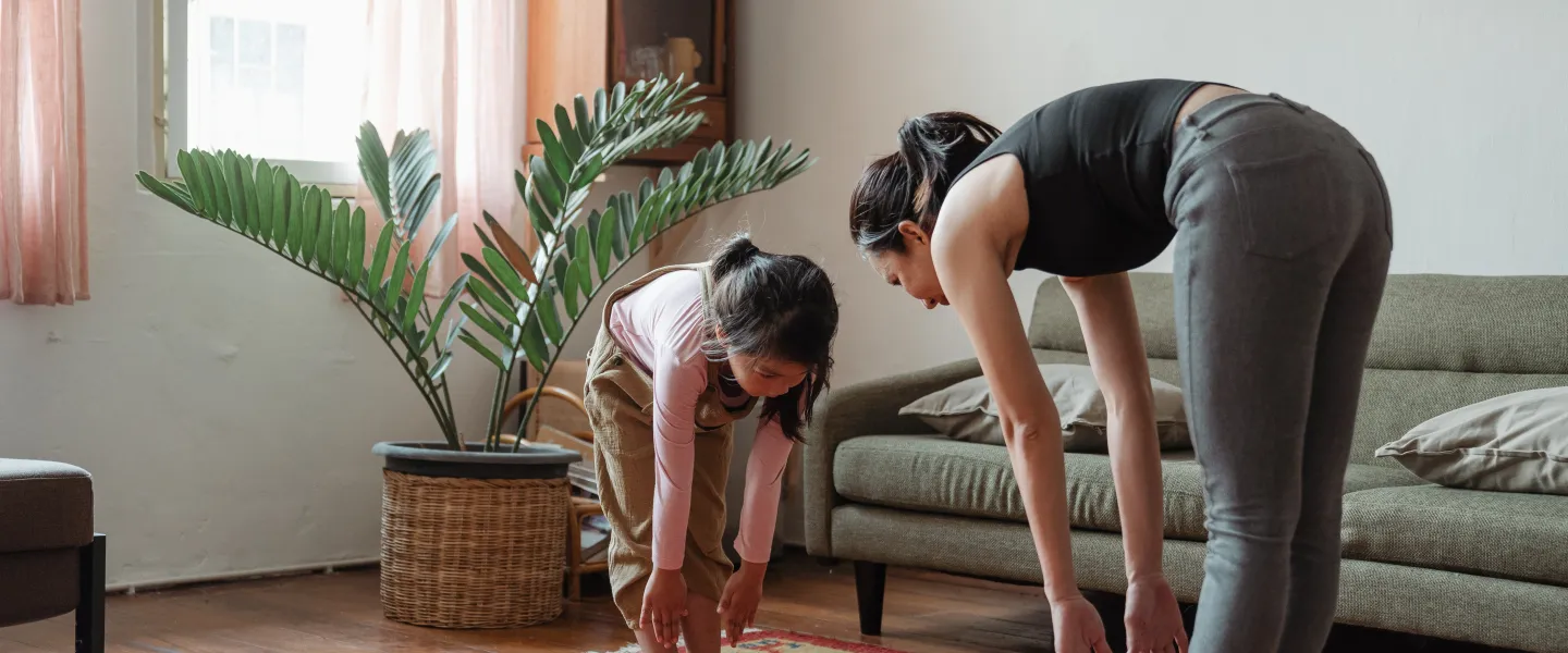 a mom and child stretching and touching their toes in their living room