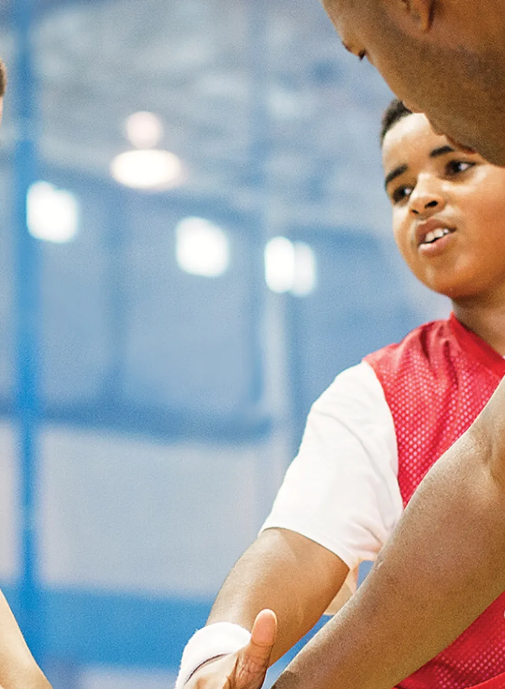 children in basketball jerseys and their coach putting their hands together for a cheer