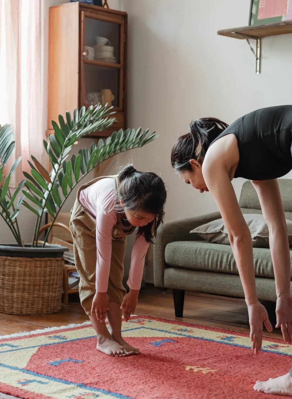 a mom and child stretching and touching their toes in their living room