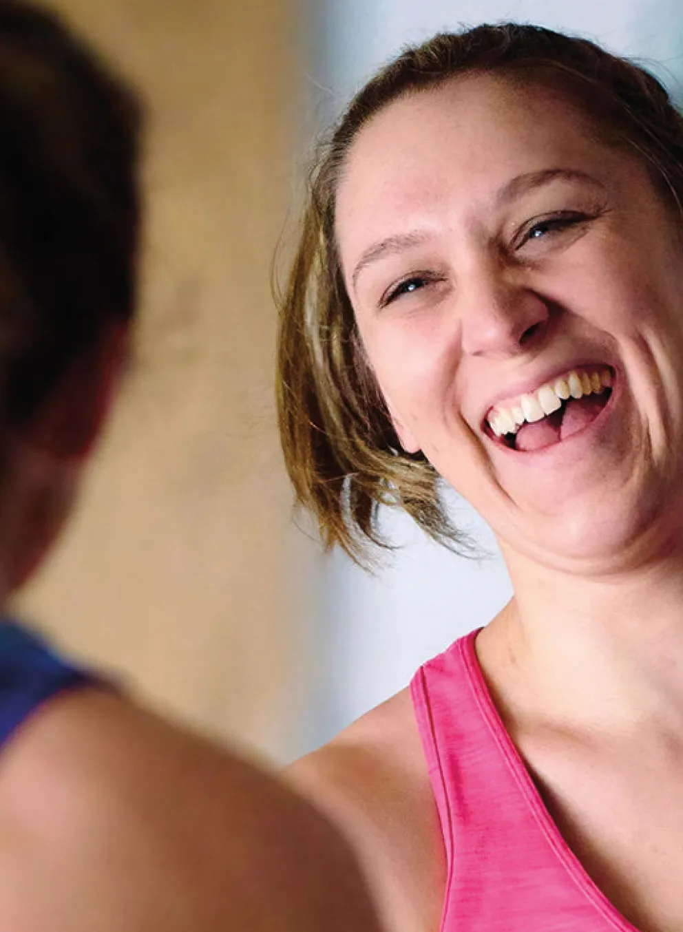 two adults in workout clothes laugh together after a fitness class