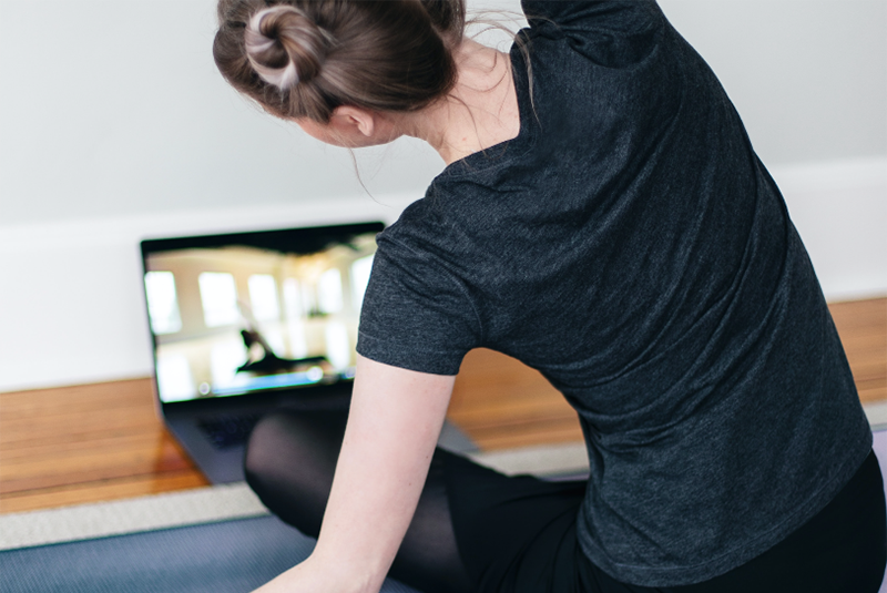 adult yoga stretching in front of a laptop