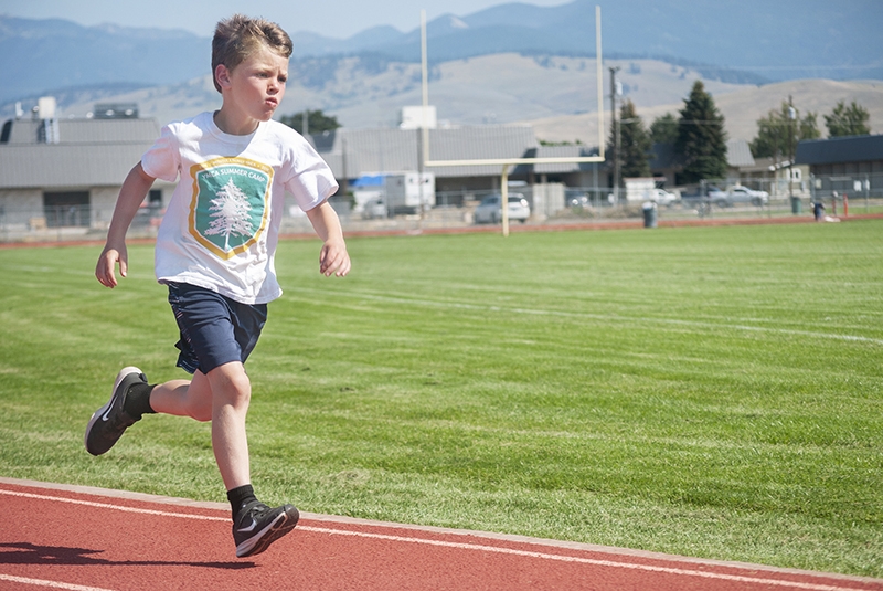 a young child runs around an outdoor track
