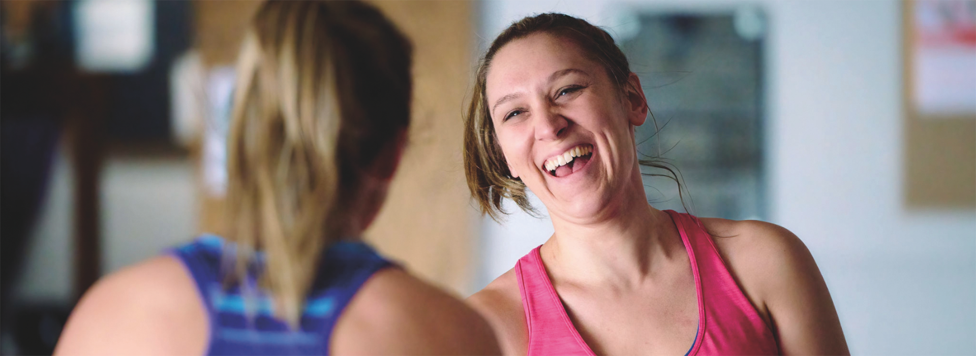 two adults in workout clothes laugh together after a fitness class 