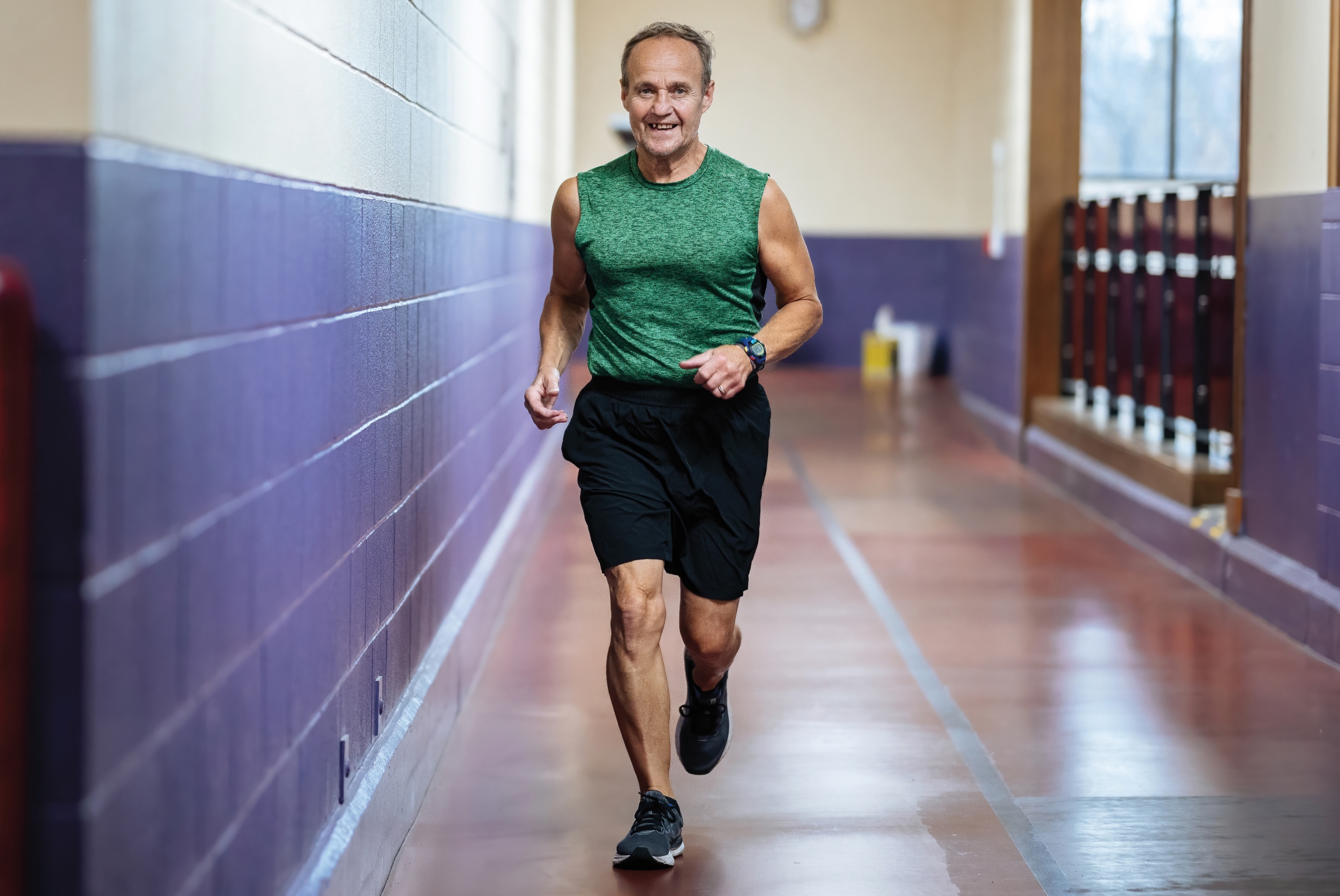an older man running around an indoor running track