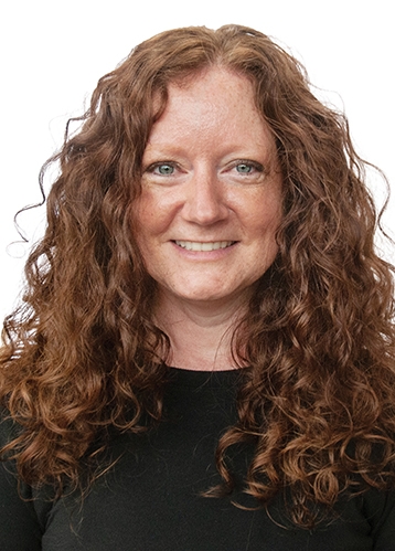 a headshot of woman with long red curly hair and green eyes