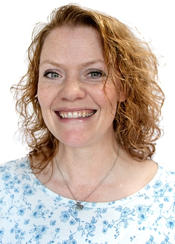 headshot photo of a smiling woman with curly orange hair