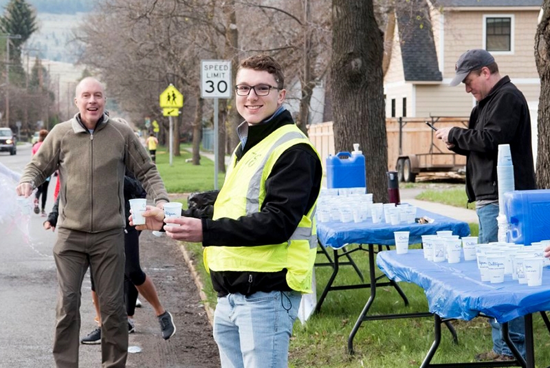 volunteers in yellow vests handing out cups of water during a running race