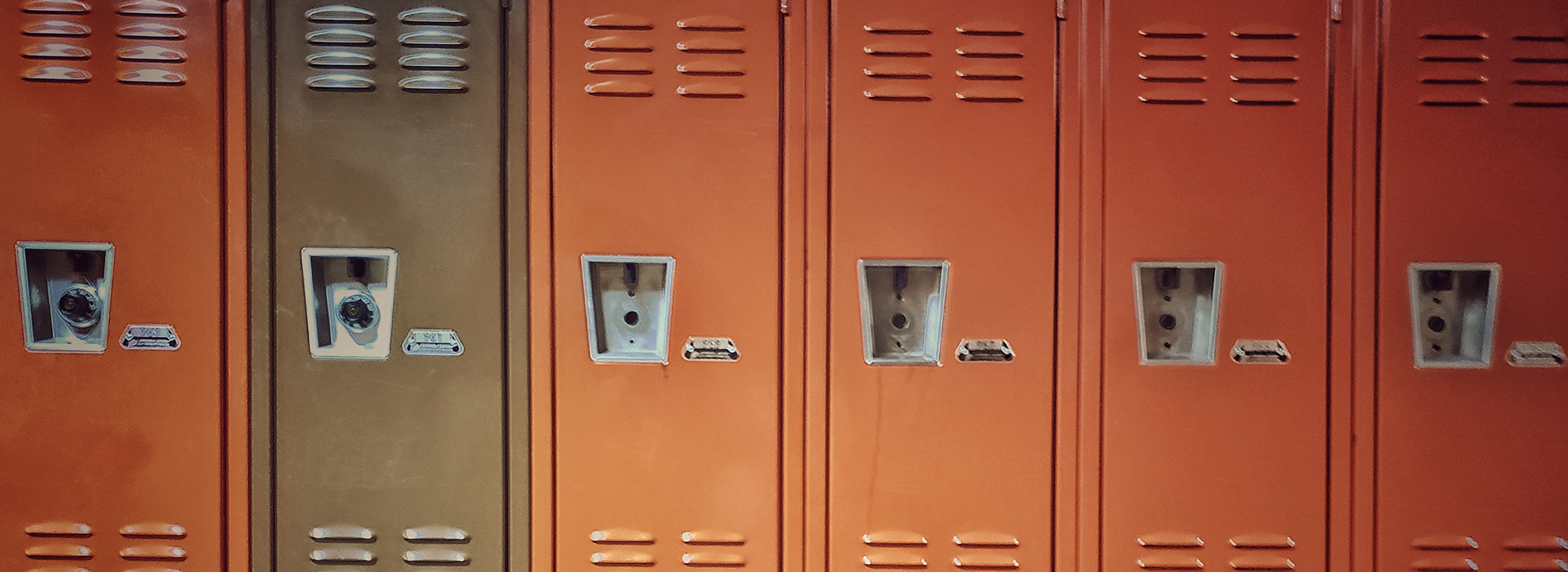 a row of metal lockers—five rusty orange lockers and one brown locker