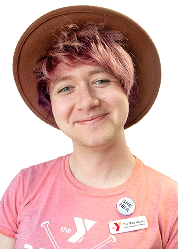 headshot of a smiling woman with pink hair wearing a pink t-shirt and a pinkish felt hat 