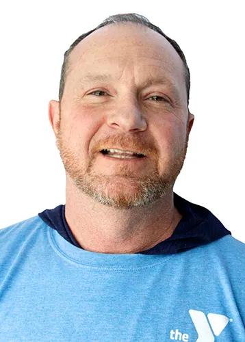 headshot photo of a smiling man with short hair and a short reddish-grey beard. he is wearing a light blue shirt with a ymca logo over a dark black shirt. 
