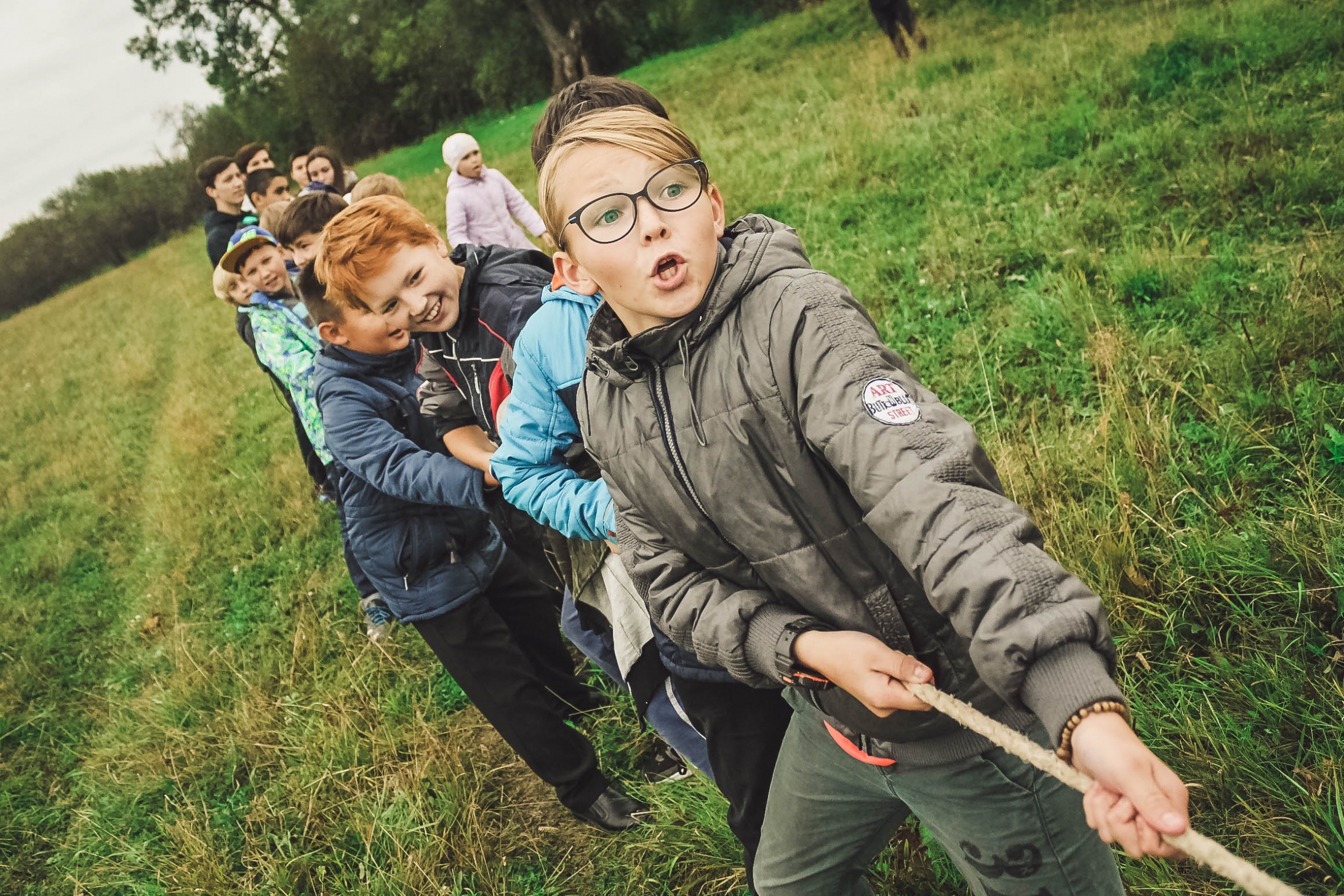 a group of children playing tug of war outside on a cloudy day