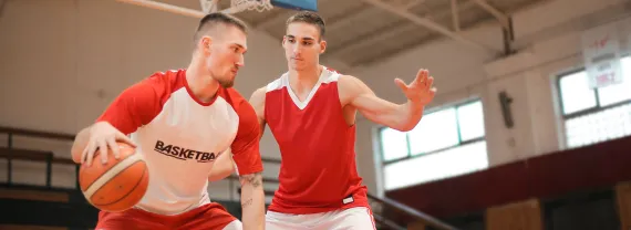 two adults playing basketball inside a gym