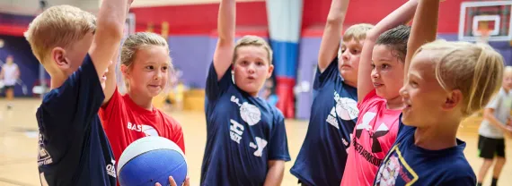 children in basketball jerseys raising their hands