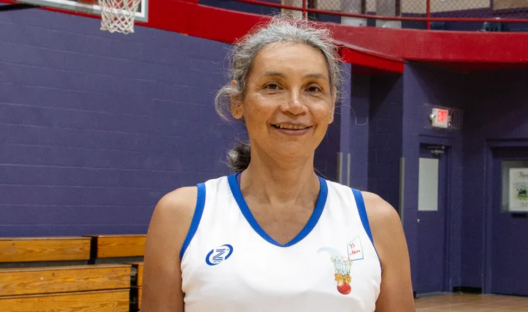 older woman wearing a basketball jersey and standing in a basketball gym
