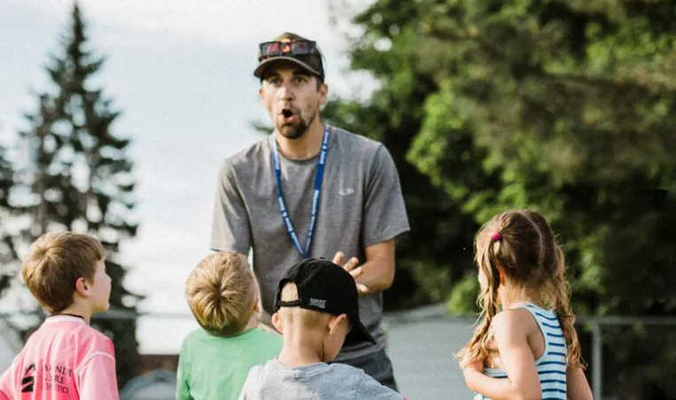 a volunteer soccer coach talking to young soccer players outside