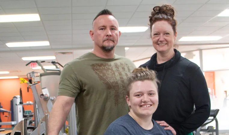 three powerlifters pose in a gym for a portrait together