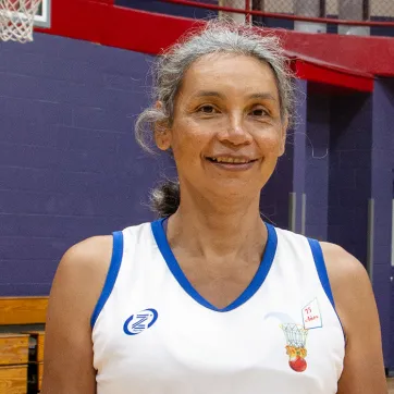 older woman wearing a basketball jersey and standing in a basketball gym