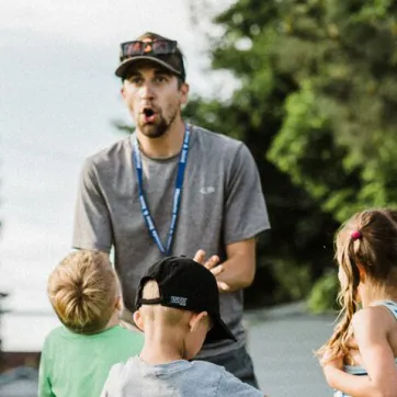 a volunteer soccer coach talking to young soccer players outside