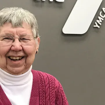 older woman with glasses smiling in a ymca 