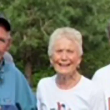 two older men and an older woman smiling at the camera after running a 10k race