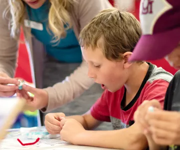 children assembling a science project together with a ymca counselor in an after school program