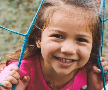 a child smiling and playing on playground equipment