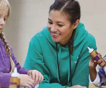an adult helping two children with an art project