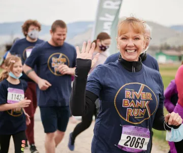 a woman smiling and waving while running a race