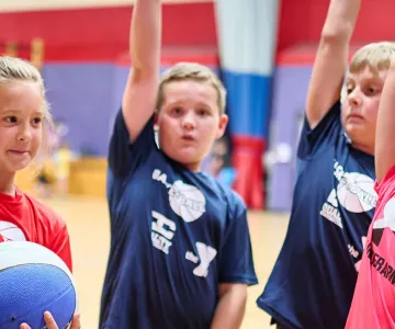children in basketball jerseys raising their hands